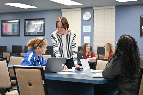 Educators standing and sitting at a table conversating