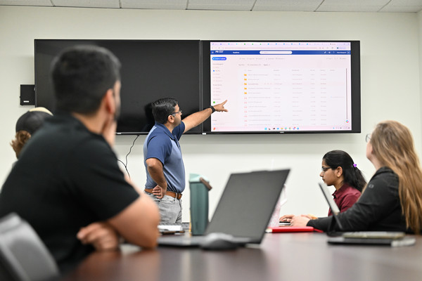 Dr. Vamsi Kalasapudi pointing at a screen in front of a class