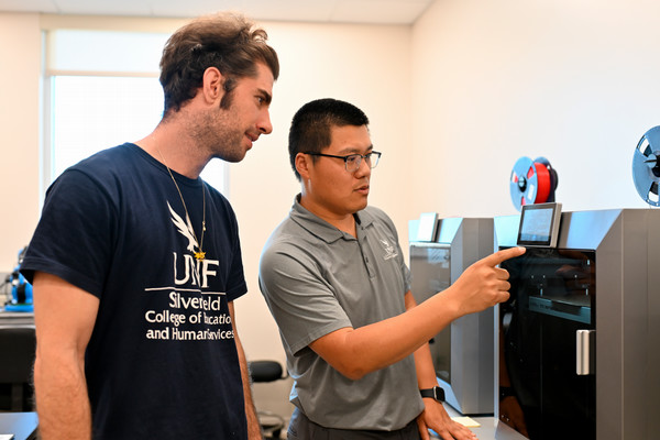 Two male UNF advanced manufacturing students working in a lab