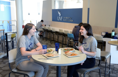 Two students sitting in Osprey Cafe conversing and smiling