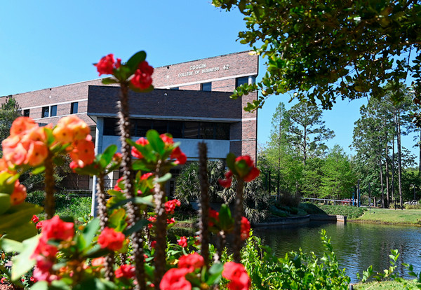 UNF Coggin College of Business building with red flowers in the foreground