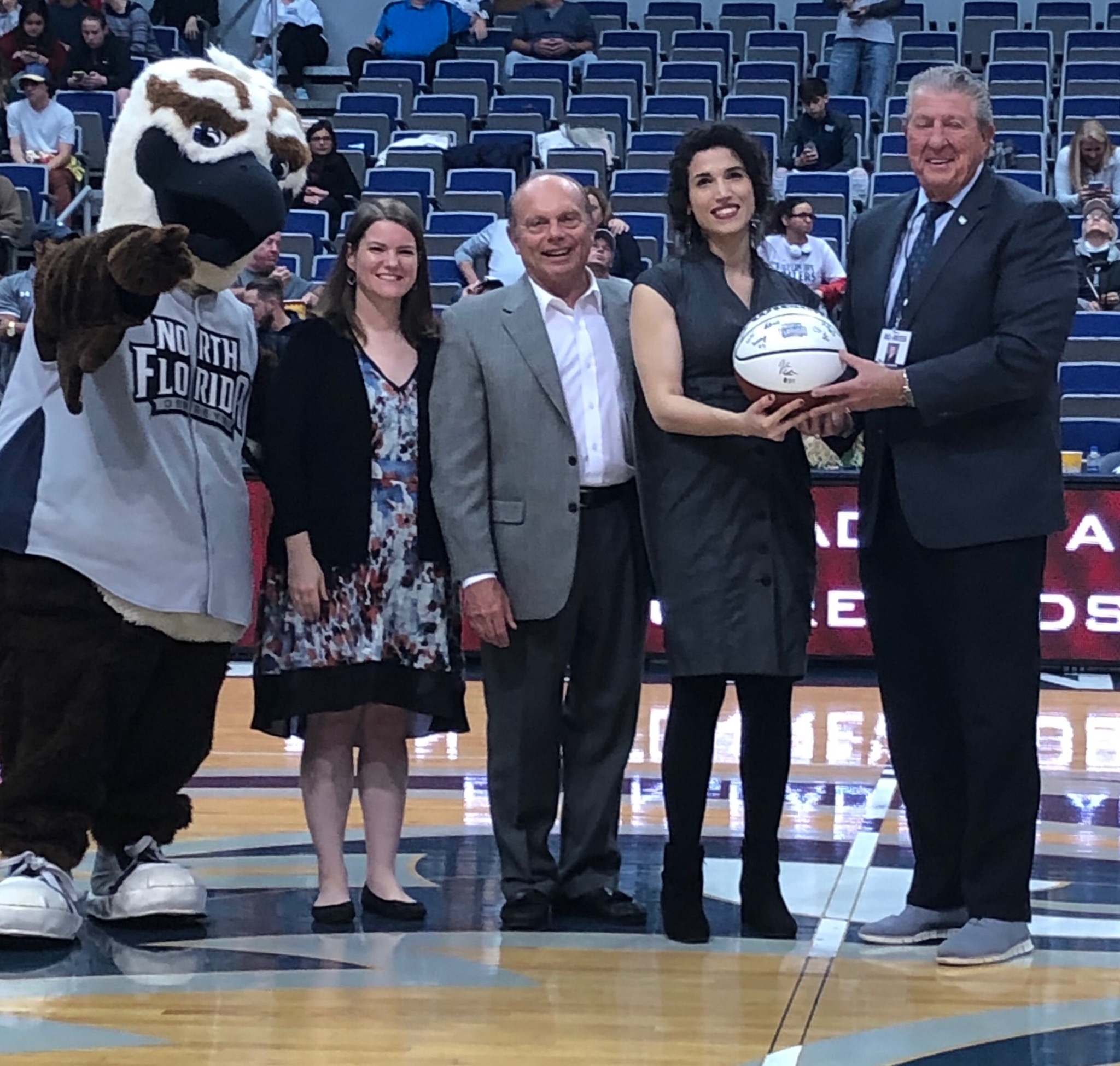 Group of people presenting Josselyn with an award at half court in the arena