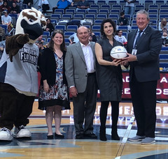 Group of people presenting Josselyn with an award at half court in the arena