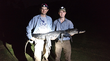 UNF researchers in field holding baby alligator