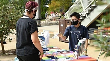 Male student tabling outside the student union passing out materials for the LGBT Resource Center
