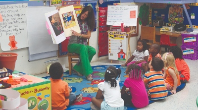 Teacher reading a book to a group of small children