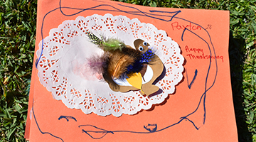 Paytons thanksgiving-themed placemat featuring a cutout of a turkey, green feathers, and pumpkins