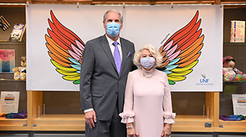 President and First Lady Szymanski posing in front of a -Wings of Pride- art installment