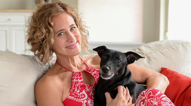 Dr. Jennifer Wesely and her dog sitting on a beige couch at home