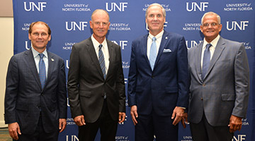 Hyde, Kitson, Szymanski and Criser posing for a photo in front of a UNF background
