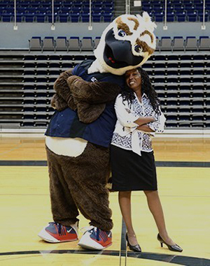 Karen Patterson and Ozzie posing on the UNF basketball court