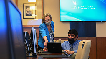 Professor assisting a student working on a laptop in the Logistics Information Technology Systems LAB