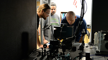 Professor and students working on equipment in the physics lab