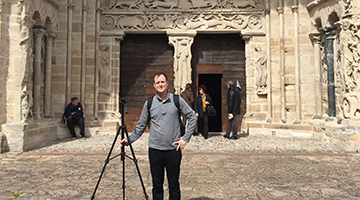 Dr. Scott Brown standing in front of a historic building with a camera on a tripod