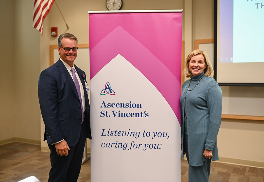 Pam Chally and Tom VanOsdol posing in front of an Ascension St. Vincent’s sign