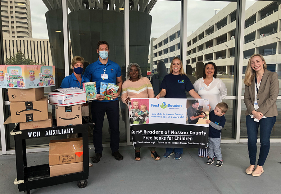 Wolfson staff in blue shirts, UNF student in middle in sweater, Ferst Coast readers staff and Dr. Jennie Ziegler donate books to Wolfson's patients