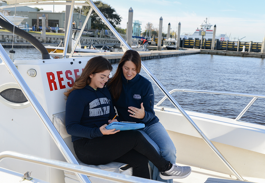 UNF student and researcher reviewing data on a research boat
