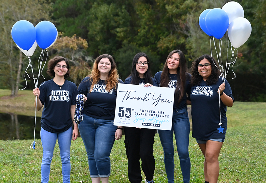 Smiling students standing with "Thank you, Donors" sign