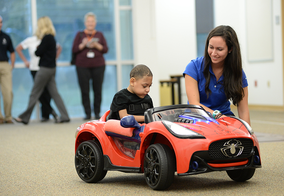 Brooks employee assisting a patient in their new adaptive toy