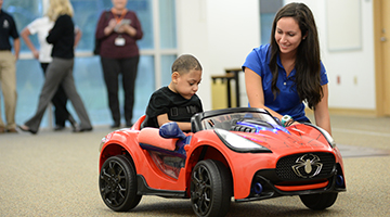 Brooks employee assisting a patient in their new adaptive toy