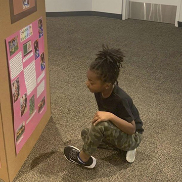 UNF Preschool students looking at a article about "Exploring the World of Color"