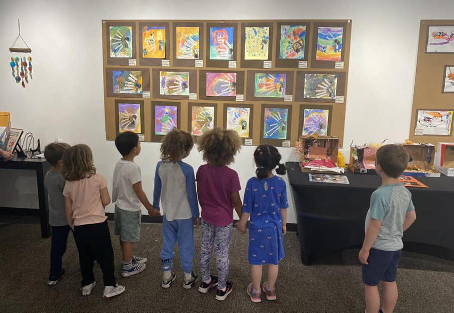 UNF Preschool students standing in front of their displayed artwork, holding hands