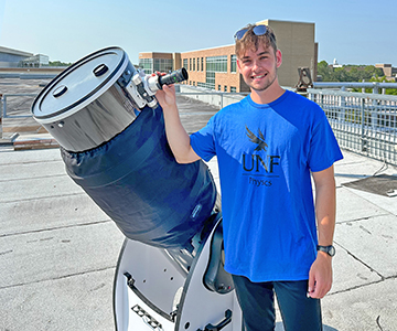 UNF Astronomy student standing beside a telescope