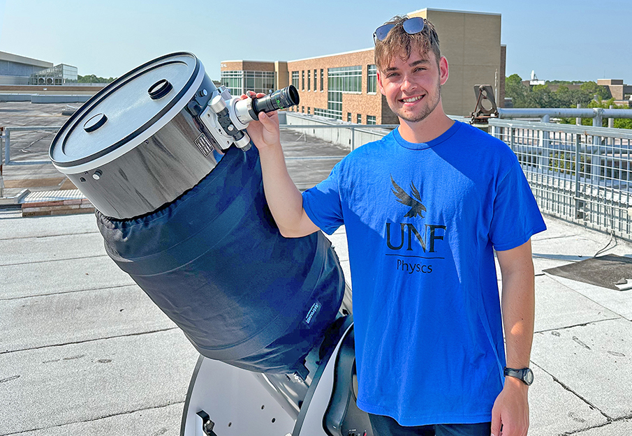 UNF Astronomy student standing beside a telescope