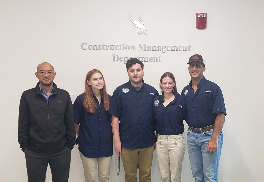 The Construction Management Ethics Team posing in front of the UNF 'Construction Management Department' sign.
