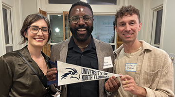 COAS alumni and student holding a UNF banner