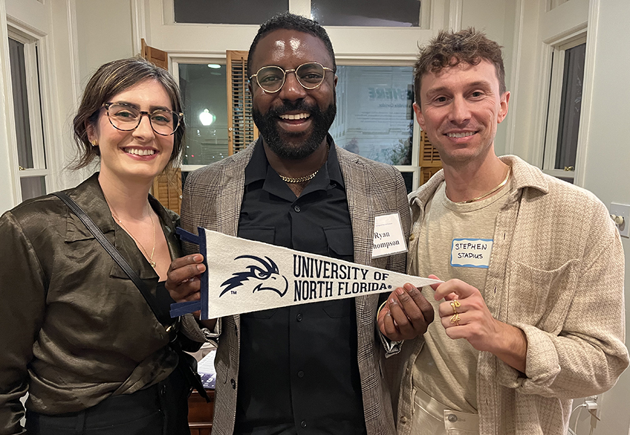 COAS alumni and student holding a UNF banner