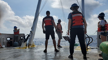 Various honors students helping bring in a net on a boat