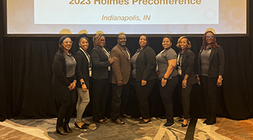 Education students who attended the Holmes Preconference posing in front of a screen that reads "2023 Holmes Preconference, Indianapolis, IN"