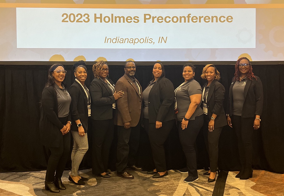 Education students who attended the Holmes Preconference posing in front of a screen that reads "2023 Holmes Preconference, Indianapolis, IN"