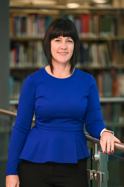 Jennifer Murray, interim dean of the UNF library posing in front of a bookshelf