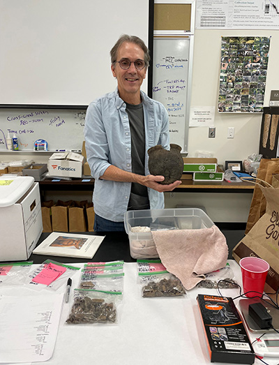 UNF's Dr. Keith Ashley holding an Indigenous artifact