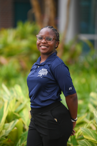 UNF graduate student Kiante (Kyaa) McClennon smiling with her hands behind her back