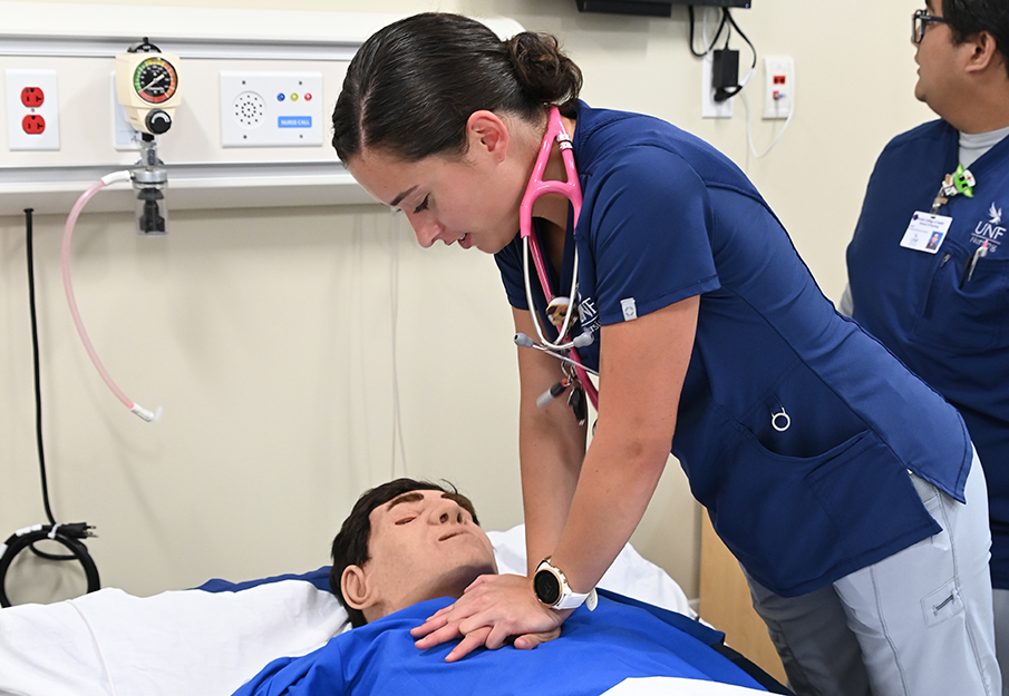 Nursing student demonstrates performing CPR on a dummy