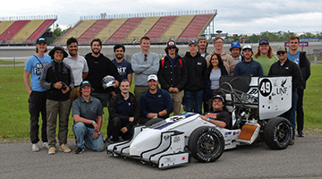 The Osprey Racing team standing together in front of the car they made