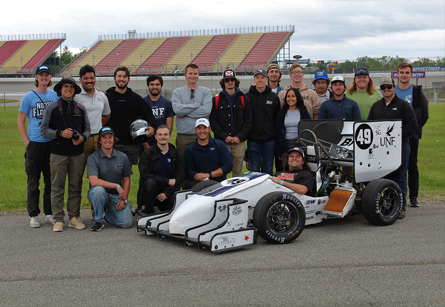 The Osprey Racing team standing together in front of the car they made