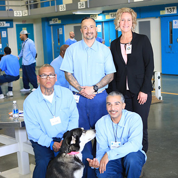 Dr. Jennifer Wesely standing beside a dog and members who benefitted from the Paws for Life program