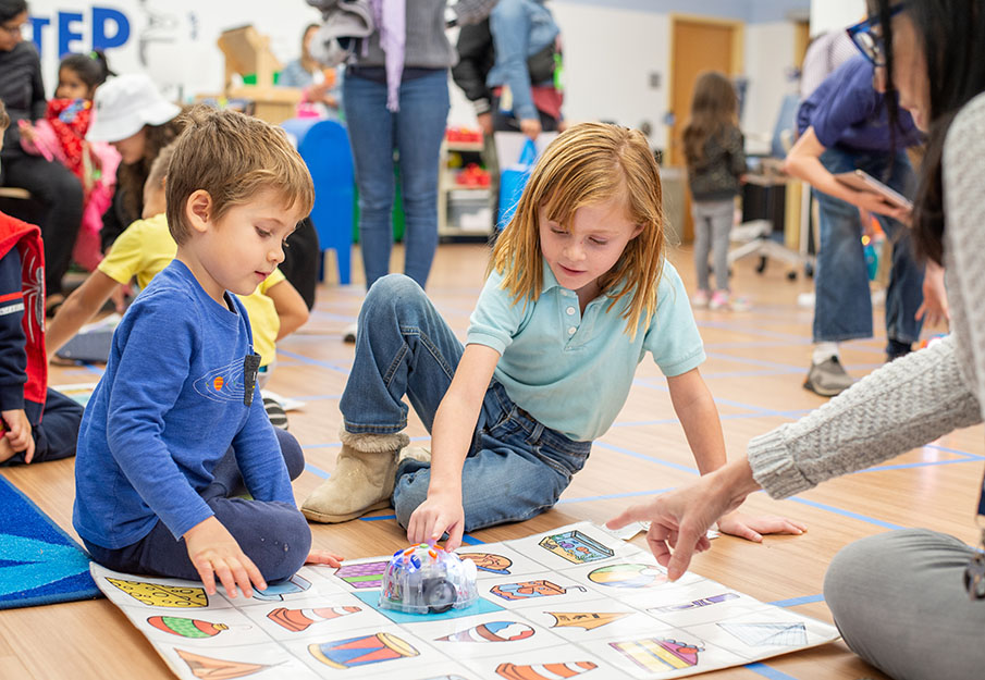 Two pre-school students participating in a science activity with a toy