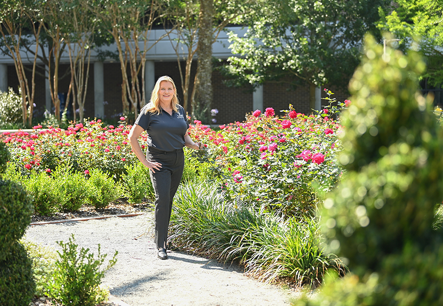 Rhonda Gracie standing next to a bush of blooming roses