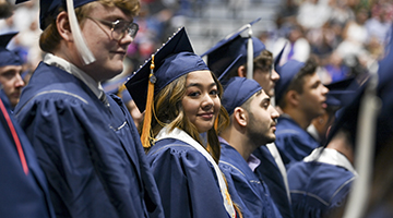 UNF graduate staring at camera amongst her peers who are looking forward