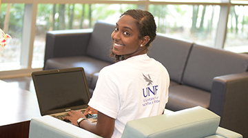 student sitting with her laptop looking at the camera 