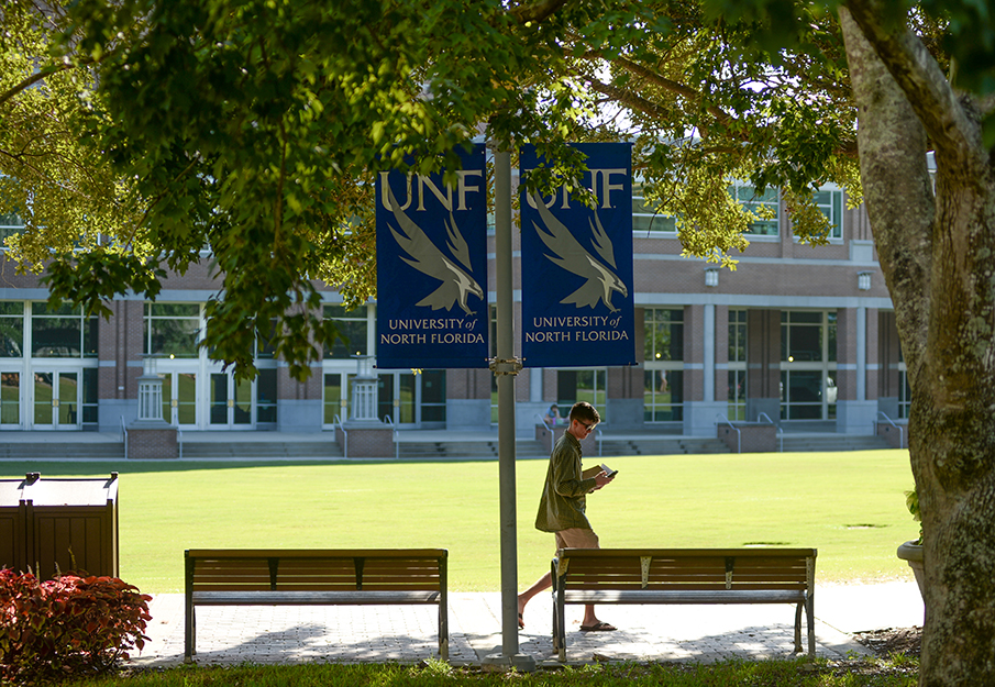 Student walking through campus near two UNF banners