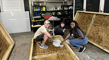 Three international students painting a prop for the Jacksonville Zoo and Gardens