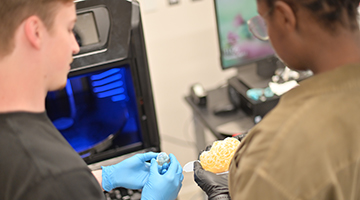 Two students putting together a 3D model of an organ