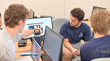 Three students looking at computers with an image of a heart