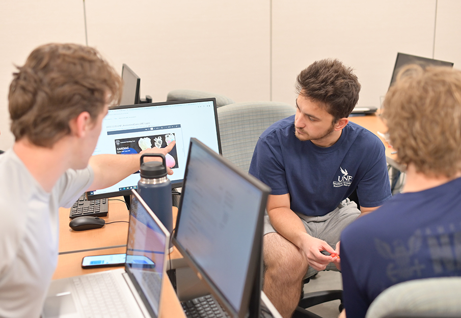 Three students looking at computers with an image of a heart